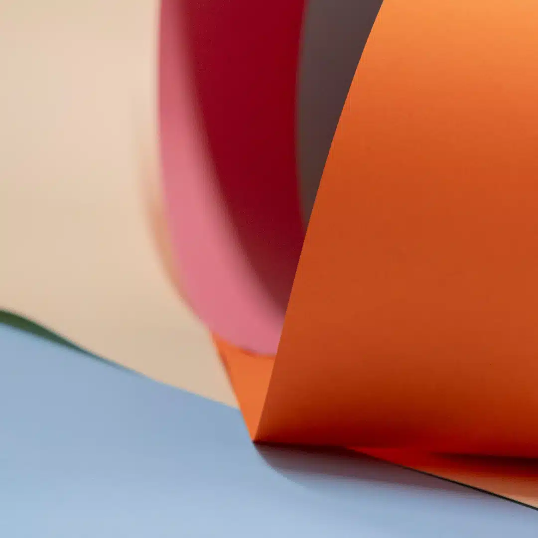 Curled sheets of red and orange paper overlapping in a layered composition